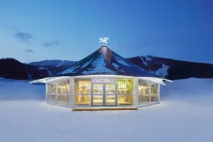 Modern retail store with glass walls and metal roof in snowy landscape