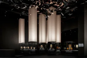 A museum exhibit gallery with illuminated display cases featuring various artifacts and sculptures.