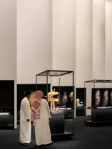 Two people observing antique artifacts in a glass case at a museum exhibit.