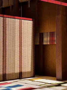 Textiles and rugs hanging on a wooden wall, showcasing various earthy and colorful patterns and textures.