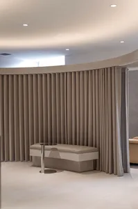 A modern minimalist spa interior featuring fabric curtains, a marble bench, and elegant lighting.
