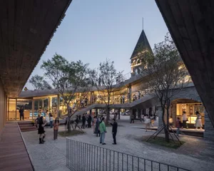 People walking through a modern public space made of brick.