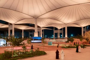 Modern, spacious urban space with a textured fabric roof structure and various functional zones.