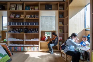 A children's library interior with wooden shelves, books, and children reading and playing.