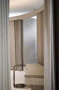 Modern minimalist living room featuring a curtain and a metal side table with a reflective surface.