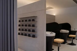 A modern hair salon featuring granite walls and porcelain sinks.