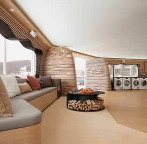 A modern living room with wooden walls, seating, and a circular fireplace with logs.