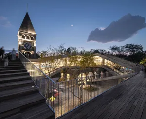 Night view of an outdoor public space featuring an illuminated architectural structure with glass and metal elements.