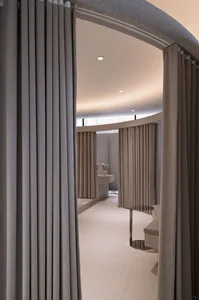 A serene spa interior featuring concrete flooring and light-colored curtains.