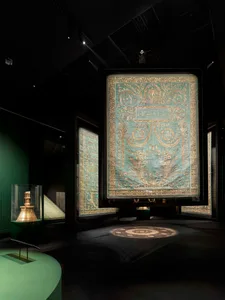 大型刺繡紡織品在博物館中展示，呈現華麗圖案與阿拉伯文字。