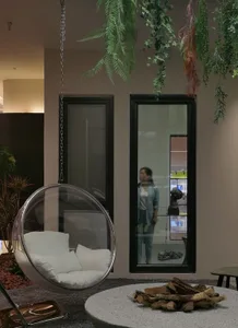 Industrial living room with wooden floor and furniture, featuring a hanging bubble chair and a fire pit with wood logs.