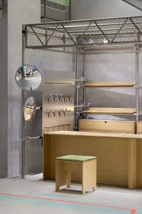 Industrial-style workshop with metal scaffolding, wooden tables, and concrete floor.