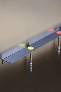 Metal wall bracket with yellow button and grey rod