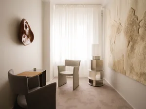 A modern minimalist living room featuring neutral textiles and metal elements.