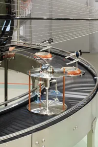 A metallic industrial machine with a globe and various components on a conveyor belt.