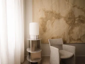 A minimalist interior design featuring a fabric lampshade and a metal side table.