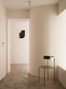 A modern, minimalist interior featuring a sleek, metallic chair with a curved backrest and seat.