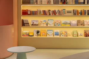 Modern children's library with plaster shelves displaying a variety of colorful books.