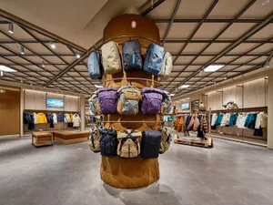 照片展示現代零售店內各種服裝商品的陳列，強調紡織品、木、鋼與陶瓷元素