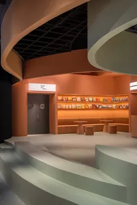 A modern library interior with concrete floors, curved walls, and a bookshelf filled with colorful books.
