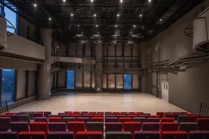 A modern theater interior featuring a concrete floor and a stage area.