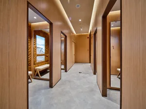A spa relaxation room with warm-toned materials and a view of a serene beach scene.