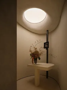 A minimalist interior design featuring a concrete table with a vase of flowers and a framed photograph.