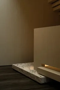 A minimalist staircase with marble steps and a wooden handrail in a modern, neutral-toned interior space.