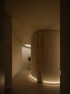 A modern corridor with curved concrete walls and illuminated floor edges.