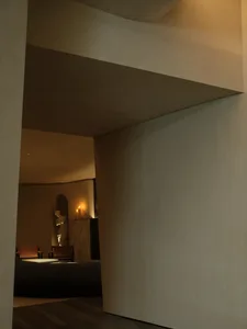 A serene minimalist interior space with neutral tones, featuring a sculpture and two candles.