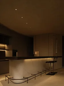 Modern minimalist kitchen with marble countertop and black stools.