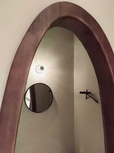 A modern interior design featuring a wooden framed arch-shaped mirror.