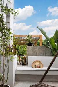 Modern living space with concrete walls, white bench, and greenery