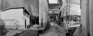 Outdoor facilities including a small building, metal sheets, and concrete structures in an urban farm setting.