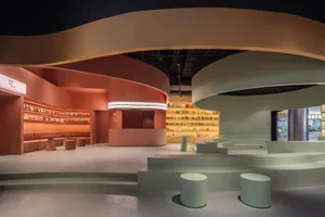 A modern library with concrete walls, floors, and benches, featuring an open space with circular seating and a circular books