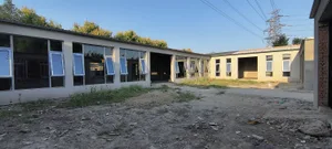 Concrete building exterior with open windows and dirt ground.