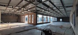 A large, industrial-style building with concrete walls and a metal roof truss system.