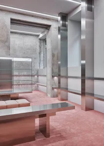 An industrial retail storefront with concrete walls, glass showcases, and steel furniture and fixtures.