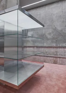 A minimalist empty display case constructed of glass and metal.