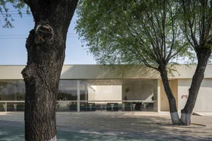 A modern building exterior with large glass windows and concrete elements.