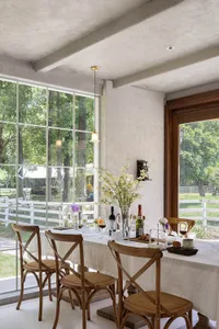 A modern dining room with wooden seating, large windows, and a table set for a meal.