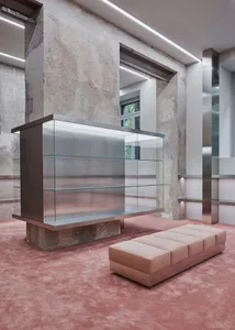 Modern lobby featuring glass showcases, concrete pillars, and metal structural elements.