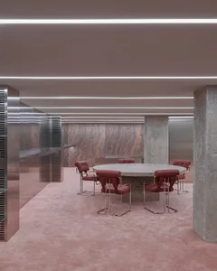 A modern office space with a marble and concrete interior, featuring a round wooden table and red leather chairs.