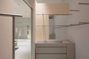 An elegant minimalist clothing retail storefront featuring a polished metallic interior design.