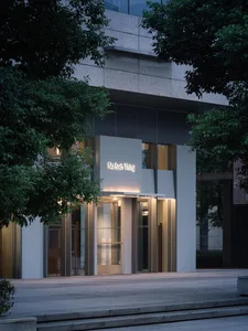 A modern glass entrance illuminated at night, featuring a sleek design and reflective surfaces.