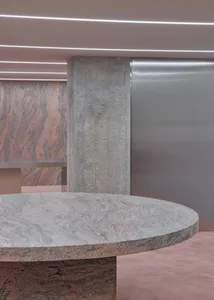Modern office space featuring a marble table with a concrete pedestal, illuminated by horizontal lighting.