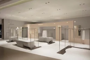 Modern retail clothing shop featuring metallic steel clothing racks and white concrete flooring