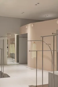 現代零售店室內，展現極簡金屬衣架與米色牆面。