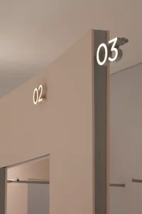 Modern storefront with illuminated metal numbers on the wall.