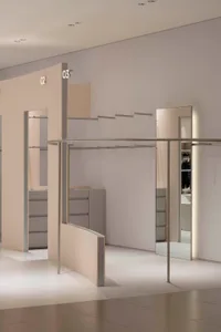 A modern minimalist clothing store with metal railings and glass partitions.